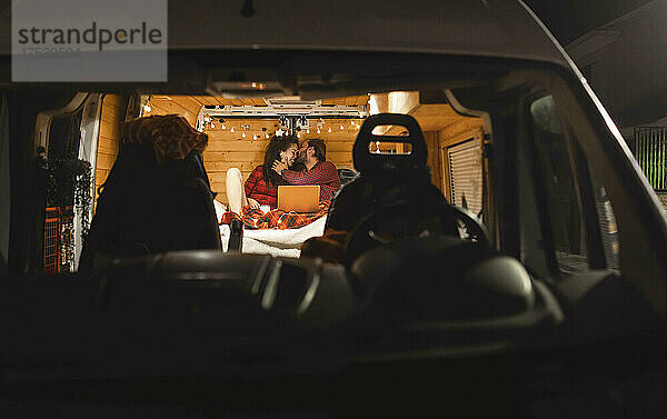 Man kissing girlfriend in camper van on vacation