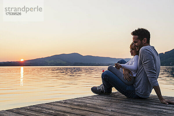 Lächelndes Mädchen sitzt auf Vaters Schoß am See  Mondsee  Österreich