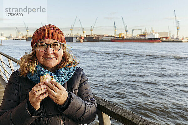 Ältere Frau isst Sandwich an der Elbe