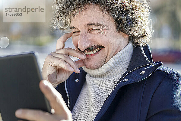 Glücklicher Mann  der an einem sonnigen Tag einen Tablet-PC nutzt