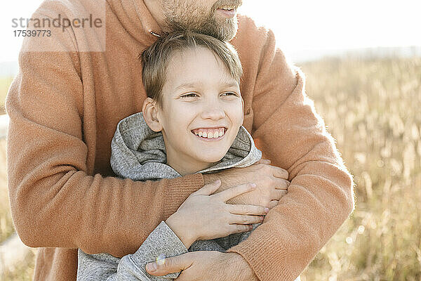 Father hugging happy son on sunny day