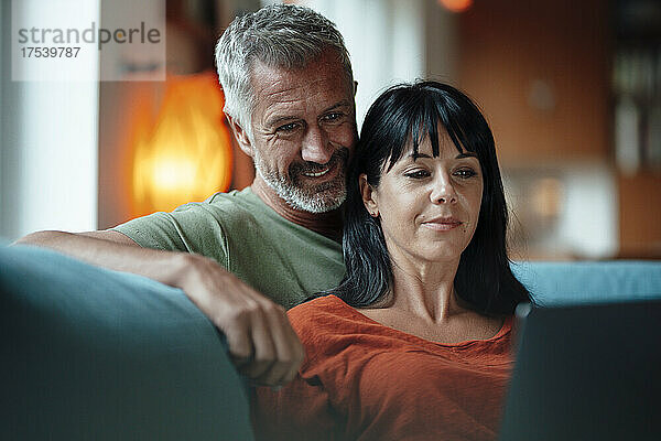 Heterosexual couple watching movie on tablet PC in living room