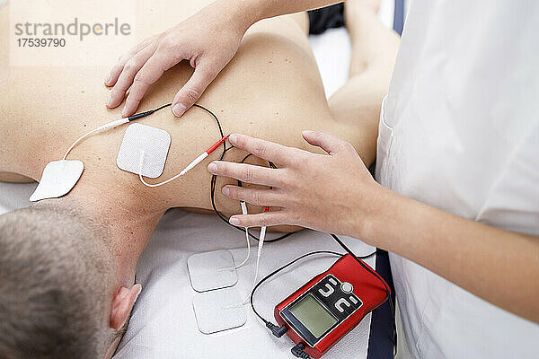 Physical therapist applying electrodes on athlete's neck