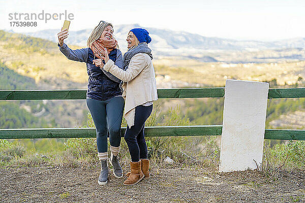 Freunde machen Selfie mit Smartphone  das an Geländer lehnt