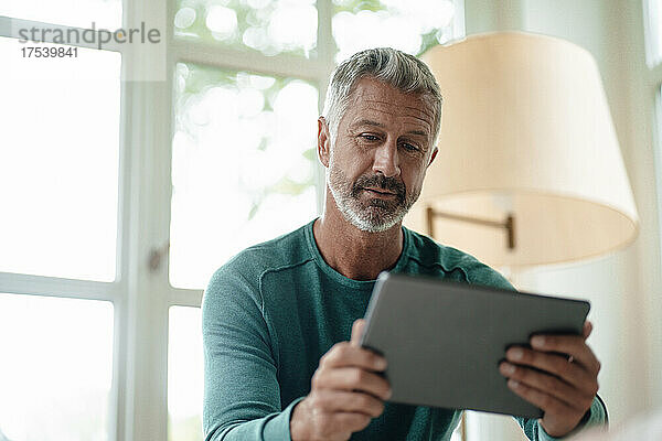 Mature man using tablet PC at home