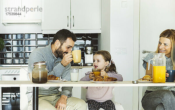 Glückliche Eltern  die zu Hause mit ihrer Tochter frühstücken