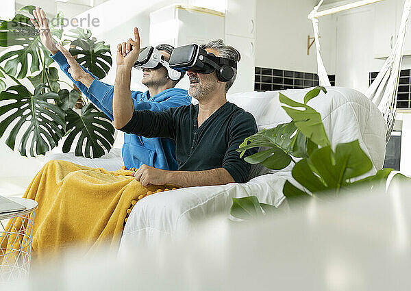 Gay couple using virtual reality headsets at home
