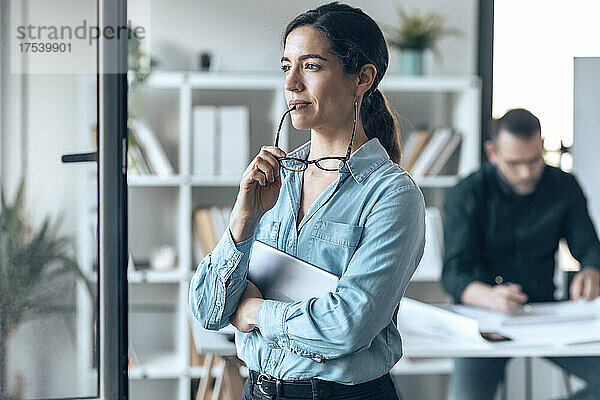 Nachdenkliche Geschäftsfrau mit Brille in kleinem Büro