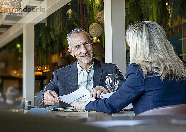 Geschäftsmann zeigt dem Kunden Dokument bei Besprechung im Restaurant