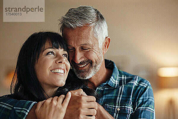 Smiling couple embracing at home