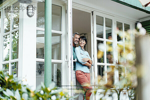Happy heterosexual couple at doorway of house