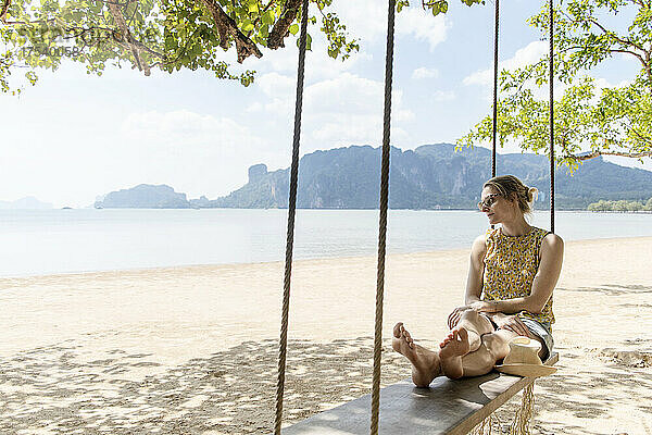 Woman sitting on rope swing at Ao Nang beach  Krabi Province  Thailand
