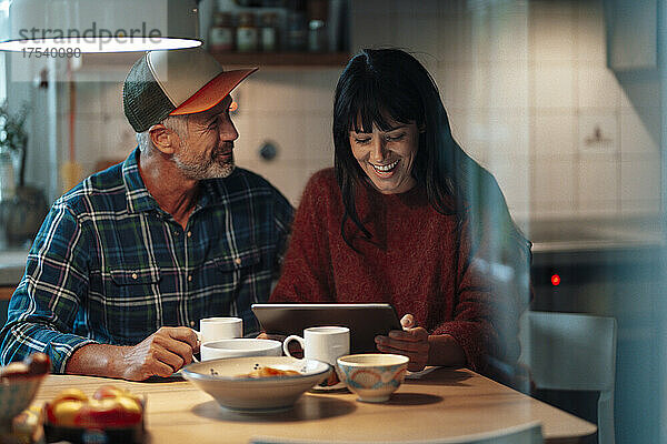 Fröhliches Paar nutzt Tablet-PC am Tisch in der Küche