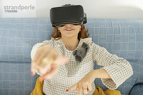 Woman gesturing wearing virtual reality headset at home