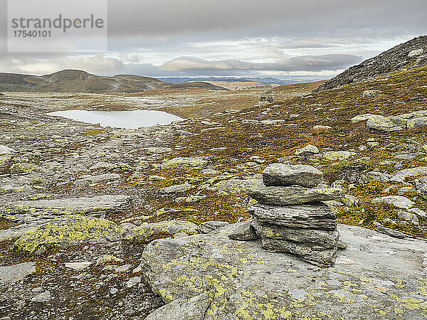 Kleiner Steinhaufen auf dem Hardangervidda-Plateau mit See im Hintergrund