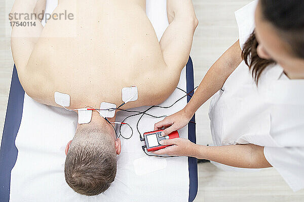 Physical therapist operating electrodes on athlete's neck