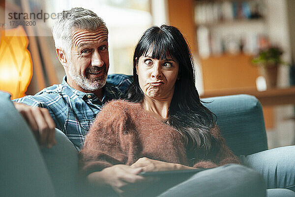 Woman making funny face by man in living room