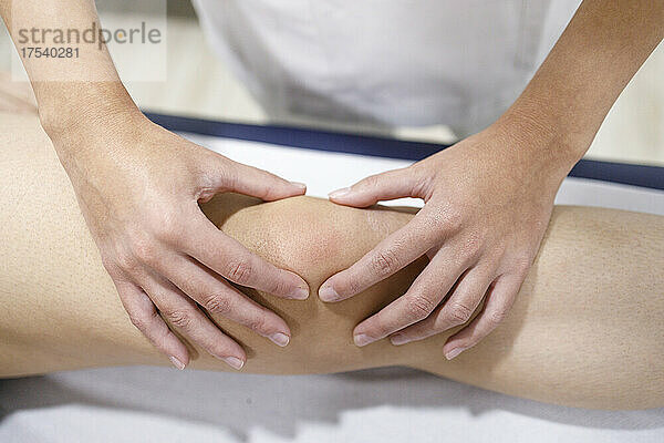Physiotherapeut massiert das Bein des Sportlers auf dem Massagetisch