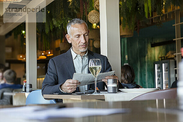 Geschäftsmann liest Zeitung und sitzt im Restaurant