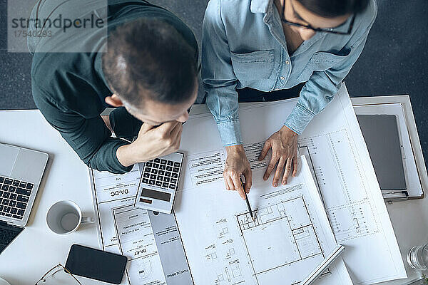 Architects discussing on blueprint in small office