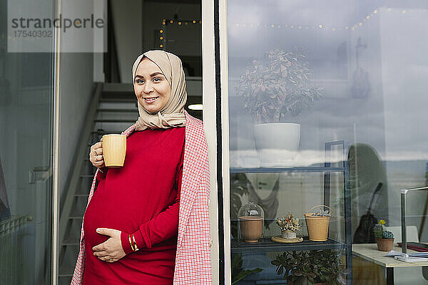 Nachdenkliche Frau mit Kaffeetasse vor der Tür