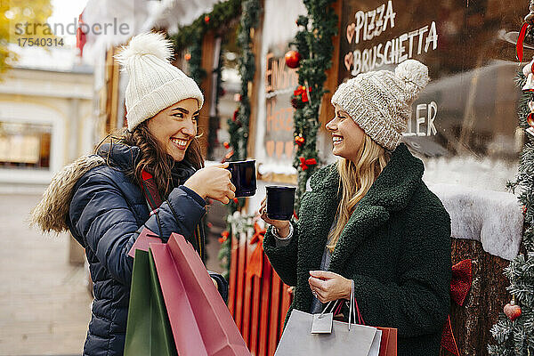 Fröhliche Freunde stoßen auf Weinkrügen auf dem Weihnachtsmarkt an