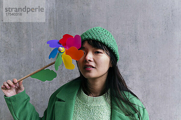 Woman covering eye with multi colored pinwheel