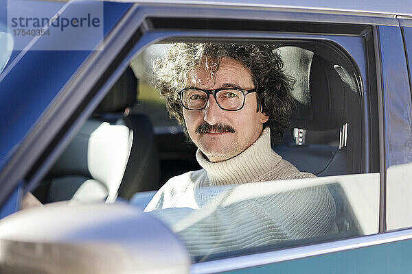 Mann mit Brille sitzt im Auto
