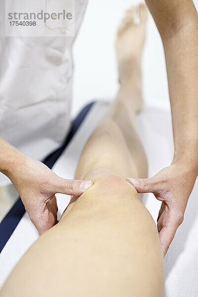 Physical therapist massaging sportsman's leg on table