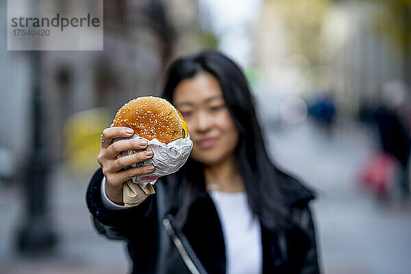Young woman holding burger in hand