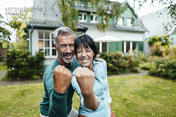 Cheerful mature couple showing fists in backyard