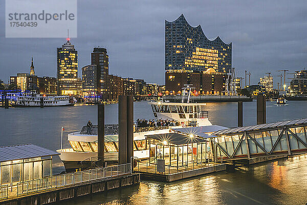 Deutschland  Hamburg  Fähre legt in der Abenddämmerung in der HafenCity an  im Hintergrund die Elbphilharmonie