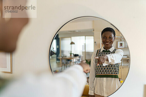 Happy woman pointing at mirror in living room