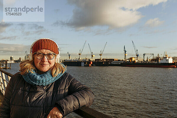 Lächelnde ältere Frau mit Kopfhörern am Hafen