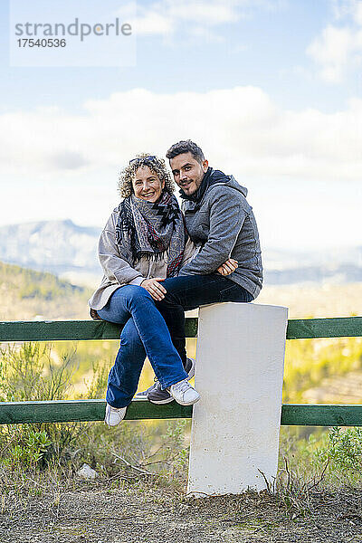 Happy couple sitting together on railing