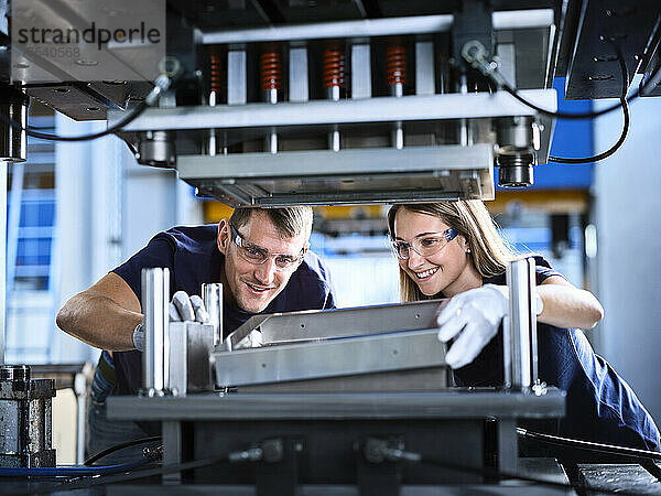 Lächelnde Kollegen  die in der Fabrik an Metallrahmen arbeiten