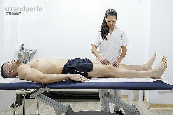 Physical therapist massaging athlete's leg at rehabilitation center
