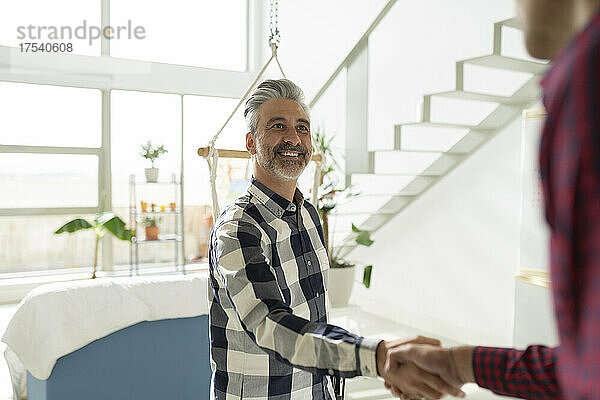 Real estate agent shaking hands with customer at home