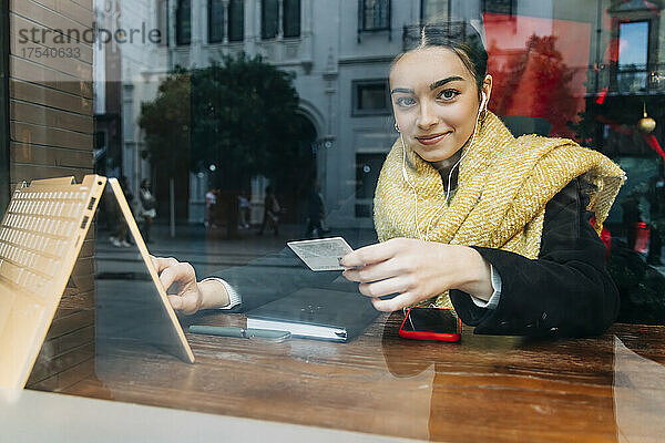 Lächelndes Teenager-Mädchen beim Online-Shopping am Laptop im Café