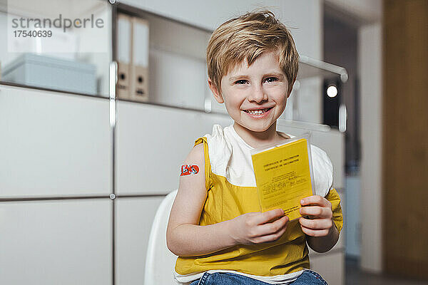 Happy boy holding immunization certificate at center