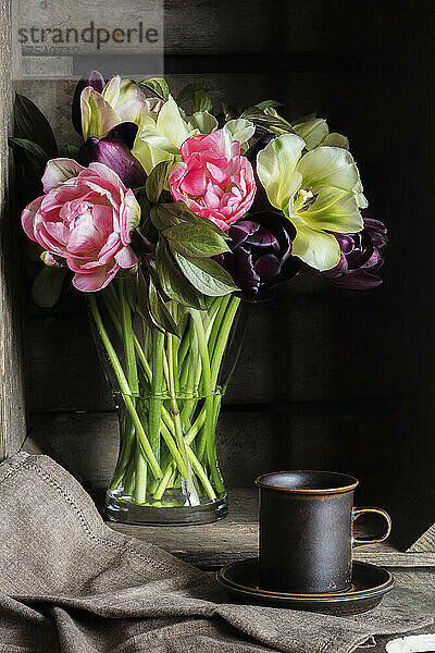 Studio shot of coffee cup and bouquet of Pink Star  Spring Green and Queen of Night tulips