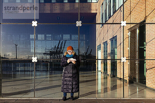 Senior woman standing in front of modern office building on sunny day