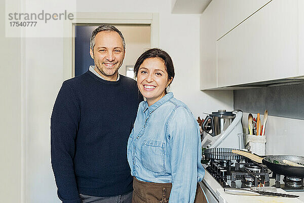 Smiling couple standing together by kitchen counter at home