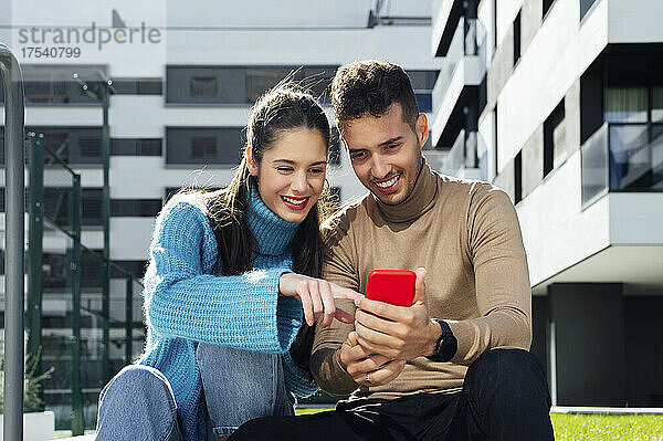 Man sharing smart phone with woman on sunny day