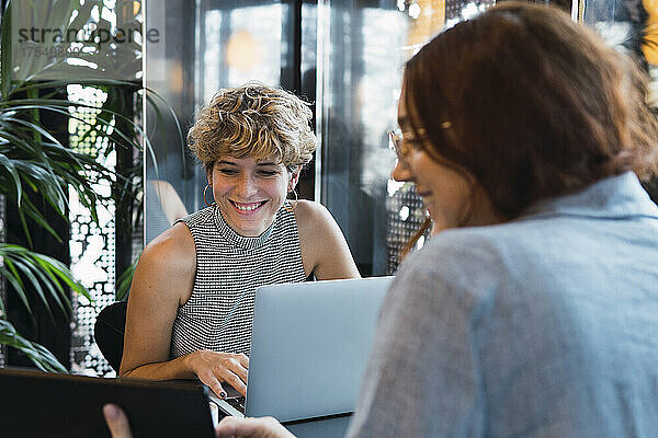 Lächelnde Geschäftskollegen diskutieren am Tisch im Café