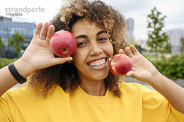 Happy young woman holding apples