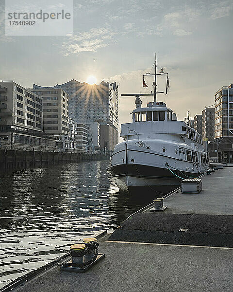 Germany  Hamburg  Boat moored in Sandtorhafen canal with sun setting over Elbphilharmonie in background