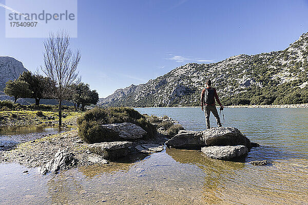 Wanderer steht auf einem Felsen und bewundert die Berge  den Cuber-Staudamm  Mallorca  Balearen  Spanien