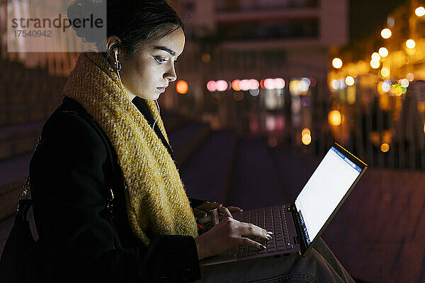 Teenage girl using laptop in city