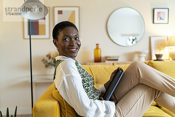 Happy woman with tablet PC on sofa at home